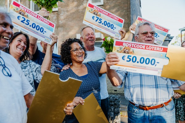 An image showing a group of the Postcode Lottery winners smiling with big cheques in their hands